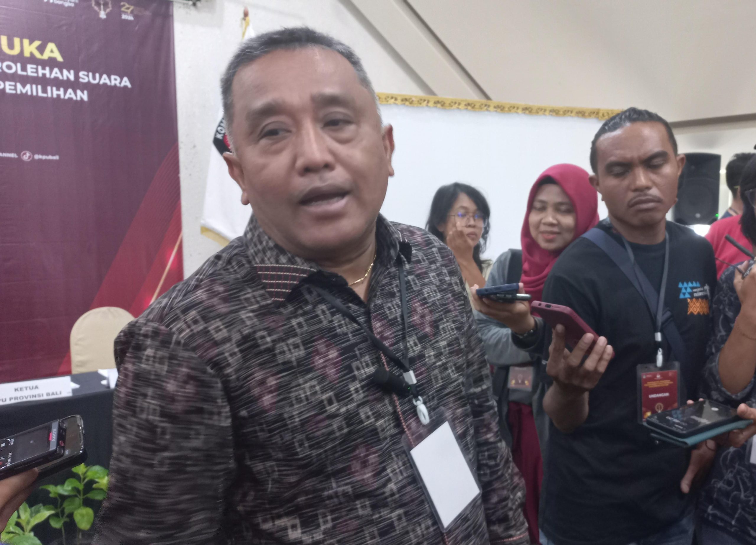 Foto: Ketua KPU Bali I Dewa Agung Gede Lidartawan saat Diwawancarai Awak Media Usai Rapat Pleno Terbuka Rekapitulasi Pilgub Bali, Minggu (8/12/24)