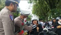 Caption: Satlantas Polres Jembrana bersama komunitas otomotif , ojol dan pelajar bagikan bunga dan gantungan kunci salam kampanye keselamatan berkendara di jalan Sudirman Jembrana, Sabtu (25/10/25). (wacanabali/Dika)